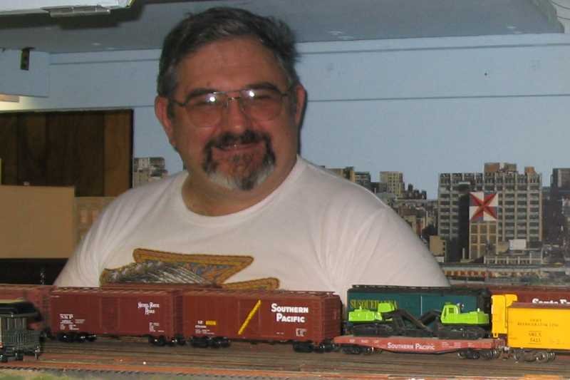 Charlie Richmond stops his job as yard master on Don Bozman's Great Great Northern layout long enough to pose for this photo.  Do you think he is having fun?